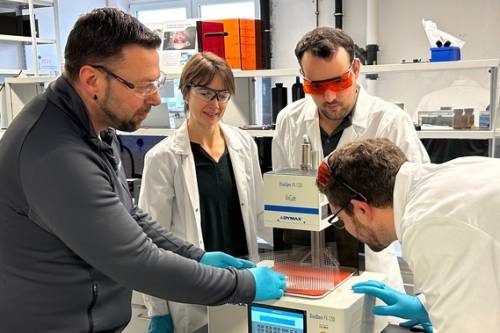 A group of employees wearing UV protective goggles and gloves while using light-curing equipment in the lab.